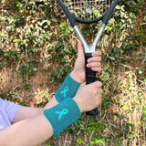 Pair of teal ribbon wristbands worn while holding a tennis racket