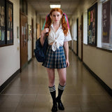 Black knee-high socks with white stripes styled with a plaid skirt and loafers